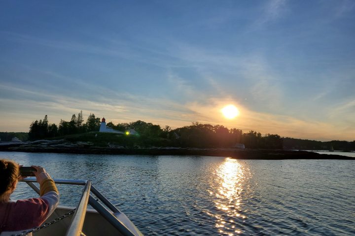 person taking photo of the sunset on a sunset cocktail cruise