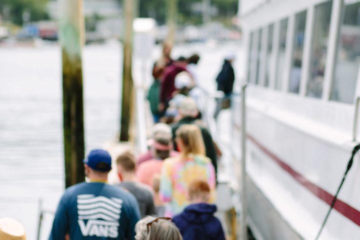 group of people lined up on dock to board the boat for a fireworks cruise